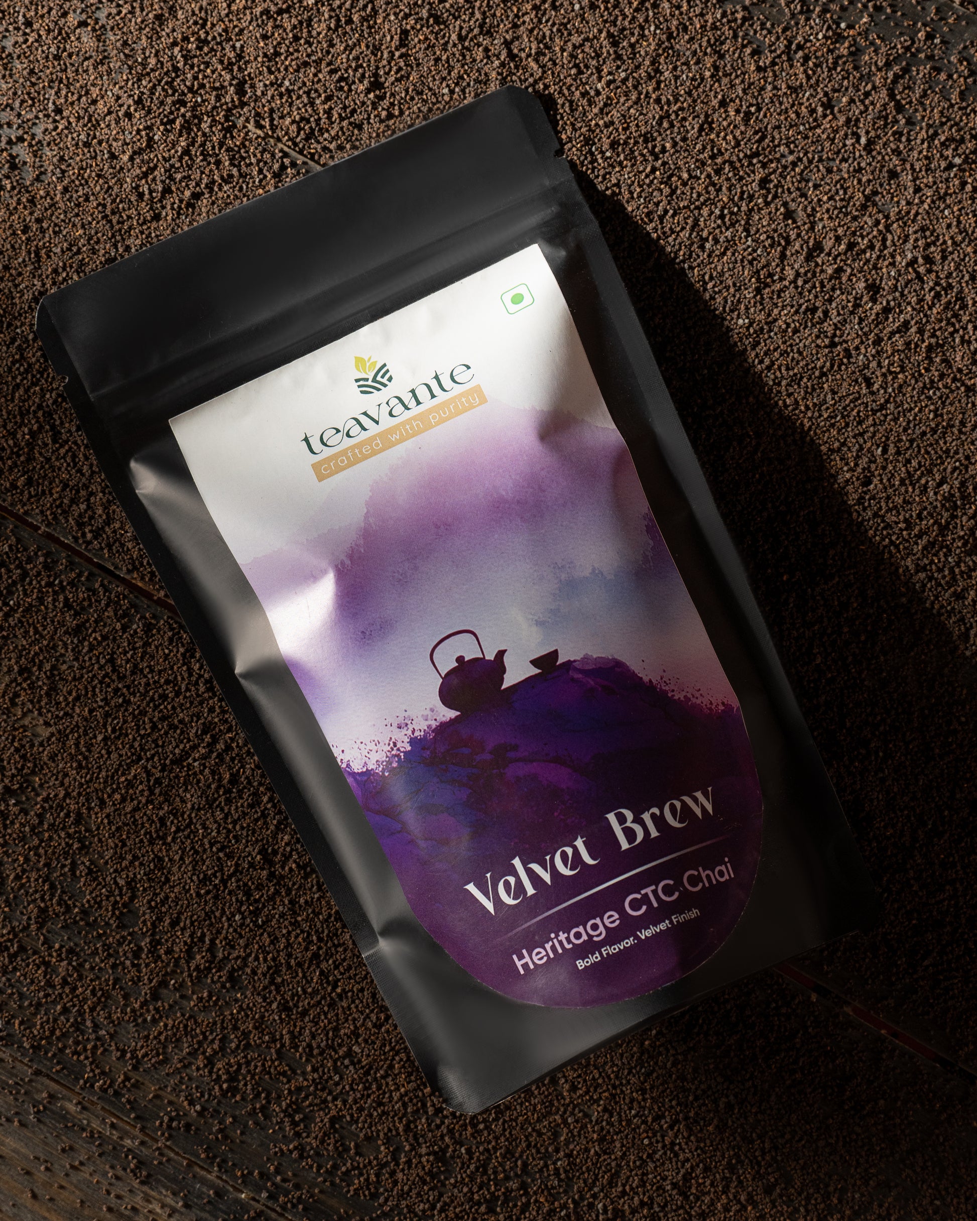 A stand-up pouch of Teavante Heritage CTC Chai 'Velvet Brew' tea, featuring a purple and white label on a matte black pouch, photographed on a dark textured surface.