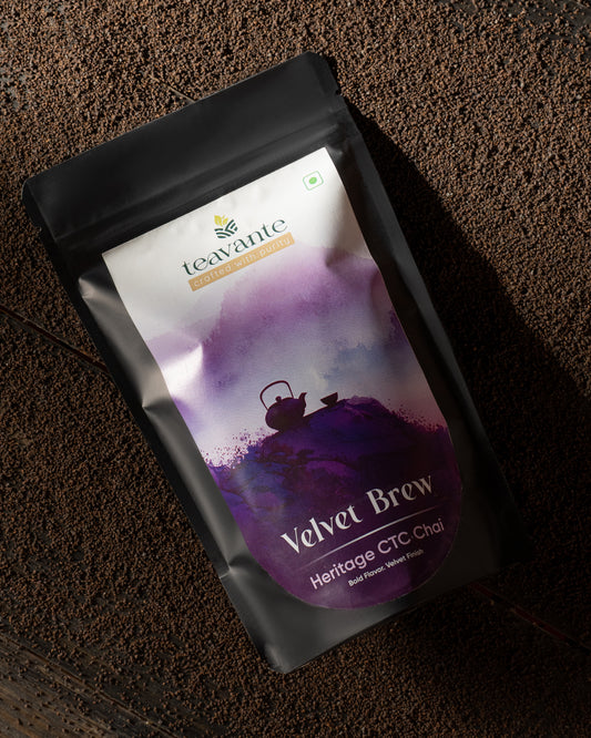 A stand-up pouch of Teavante Heritage CTC Chai 'Velvet Brew' tea, featuring a purple and white label on a matte black pouch, photographed on a dark textured surface.